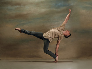 Fototapeta premium The young man dancing in contemporary stile of ballet at studio on gray background