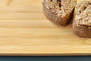 Two slices of rye homemade homemade bread on a bamboo cutting board on a black background. Copy Space.