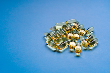 Close up capsules of fish fat oil, omega 3, vitamin e on the blue background. Healthy food diet. Nutritional supplement