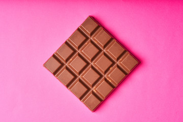 Bar of milk chocolate on a colored paper background