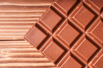 Milk chocolate bar on wooden background, macro photo