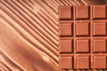 Milk chocolate bar on wooden background, macro photo