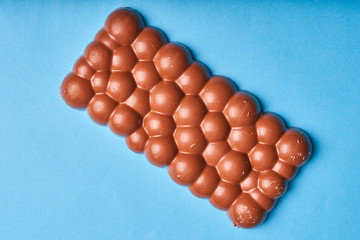 Bar of milk chocolate on a colored paper background