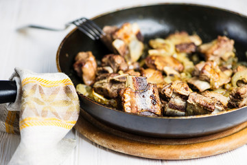 fried veal ribs in a sauce with onions in a pan