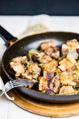 fried veal ribs in a sauce with onions in a pan