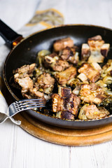 fried veal ribs in a sauce with onions in a pan