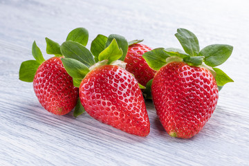 Four strawberries fruits on a white wood background