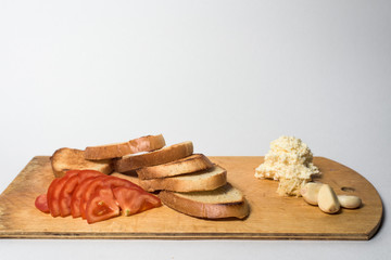 ingredients for sandwich, tomato toast, bread, and garlic. lies on a wooden kitchen Board. white background