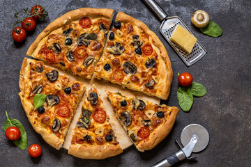pizza with tomatoes, cheese, mushrooms, olives and spinach on a dark background