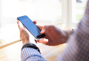 Close up of man's hands holding cell telephone with blank copy space scree for your advertising text message or promotional content, hipster man watching on mobile phone. 