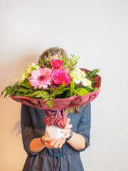 Junge Frau mit bunten Blumenstrauß vor dem Gesicht