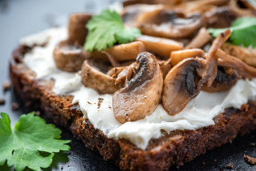 Bruschetta with mushrooms and ricotta closeup on a black background.