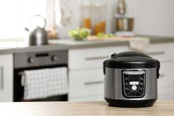 Modern electric multi cooker on table in kitchen. Space for text