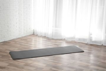 Grey yoga mat on floor indoors. Space for text