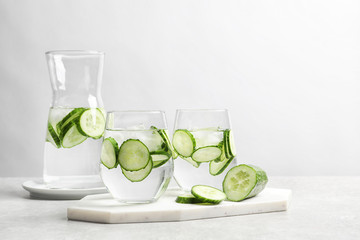 Fresh cucumber water in glassware on table against light background. Space for text