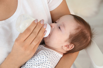 Obraz na płótnie Canvas Woman feeding her baby from bottle at home, closeup