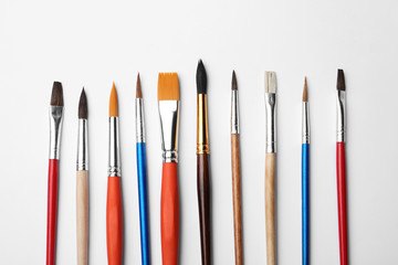 Fototapeta premium Different paint brushes on white background, top view