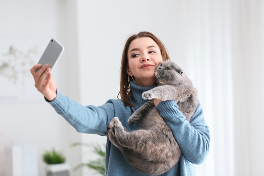 Young woman taking selfie with her cute cat at home