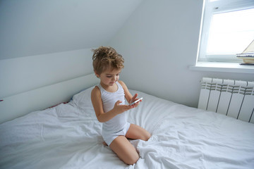 Boy playing on electronic gadget tablet in his bedroom. Social problem of communication of children in the modern world.