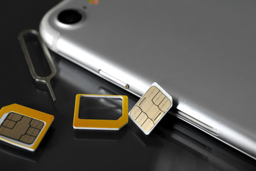 Mobile phone with sim cards and key on dark table - obrazy, fototapety, plakaty