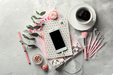 Composition with mobile phone, cup of coffee and female items on grey background