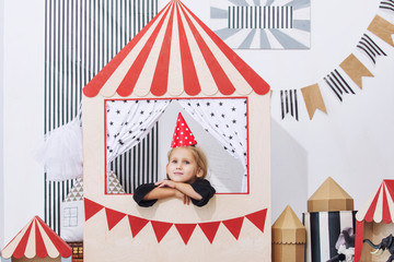 Little beautiful child girl in the children's playroom playing in the festive circus