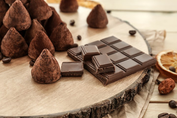 Wooden board with tasty sweet truffles on table, closeup