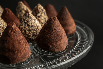 Dessert stand with tasty sweet truffles on dark background, closeup