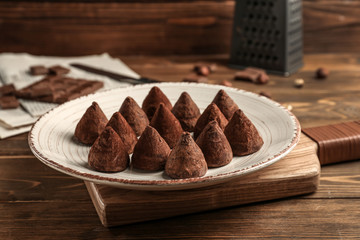 Plate with tasty sweet truffles on wooden table