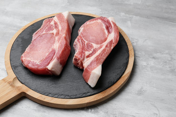 Wooden board with tasty raw meat on grey background
