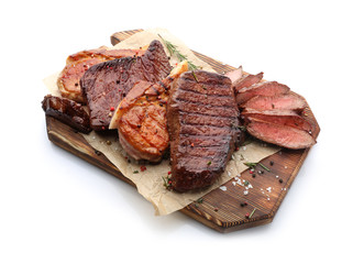 Wooden board with different tasty cooked meat on white background