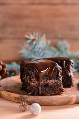 Wooden plate with pieces of tasty chocolate cake on table