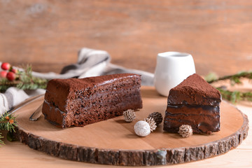 Wooden board with pieces of tasty chocolate cake on table