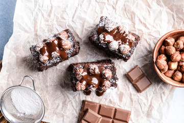 Pieces of tasty chocolate cake with hazelnuts on parchment