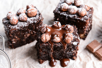 Pieces of tasty chocolate cake with hazelnuts on parchment