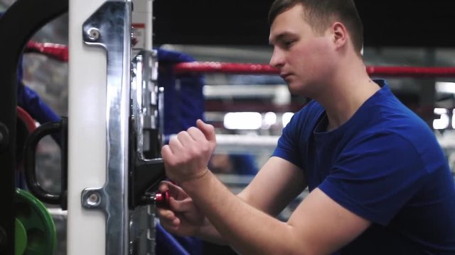 Male adjusting olympic bar before squats workout in the gym Shallow depth of field.