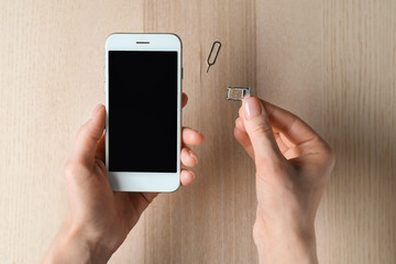Woman inserting sim card into mobile phone, top view