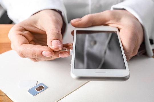 Woman opening sim card slot with key, closeup