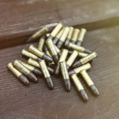 Small caliber cartridges for rifle on wooden background
