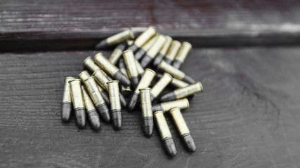 Small caliber cartridges for rifle on wooden background