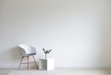 Fototapeta Stylish chair with shelf near white wall in room obraz