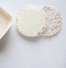 Healthy organic rice cakes with cream cheese on white marble.