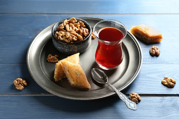 Glass of tasty Turkish tea, baklava and walnuts on table