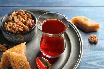 Glass of tasty Turkish tea, baklava and walnuts on table