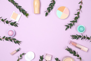 Set of makeup cosmetics with eucalyptus branches on color background
