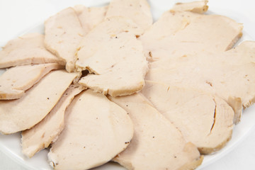 Sliced meat pieces, bacon, cold boiled pork, balyk on a white plate. Isolated on white background. Snack. Meat dish. Closeup