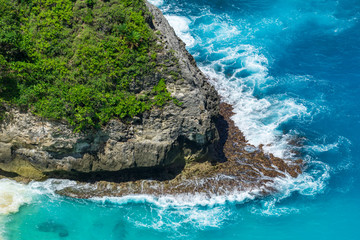 Vertiginous, swirling foamy water waves at the ocean photographed from above cliff.