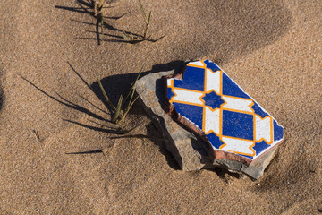 Broken ornate tile in the sand, Morocco