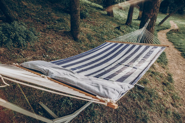 Stylish striped hammock hanging outdoors at nature resort close-up, blue and white stipes on...