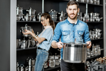 Couple choosing pans for cooking in the shop